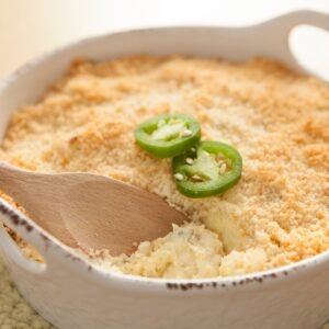 jalapeno popper dip in a white bowl with a wooden spoon