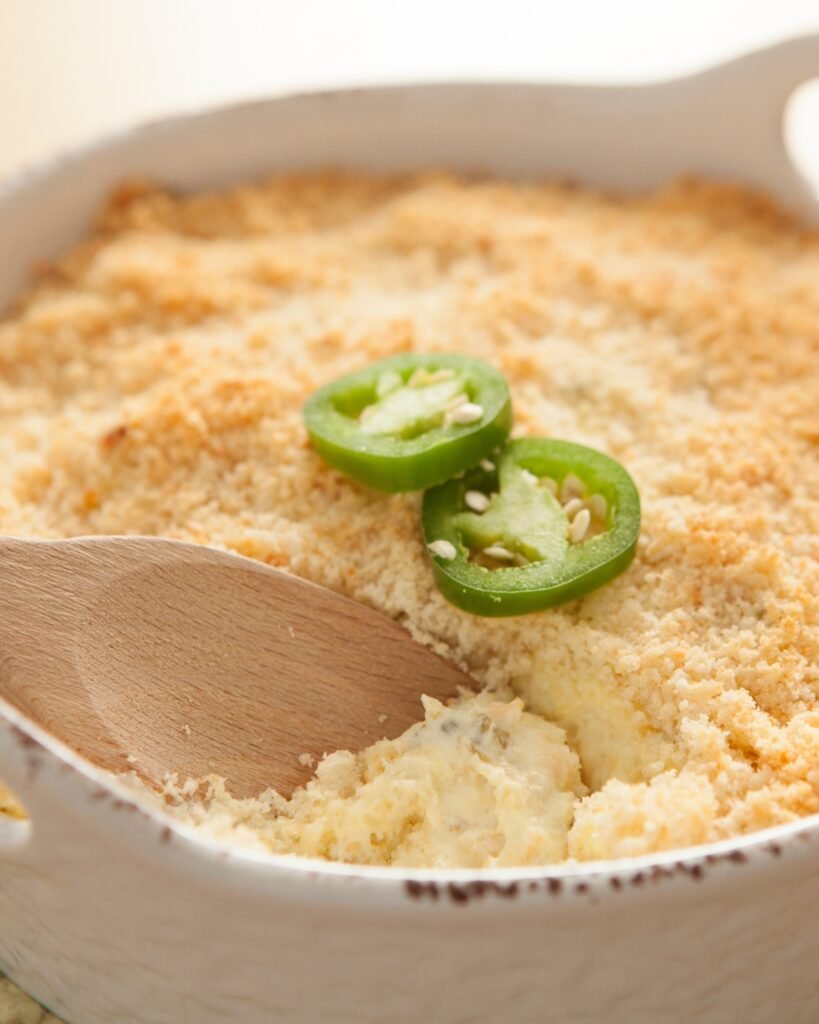 jalapeno popper dip in a white bowl with a wooden spoon